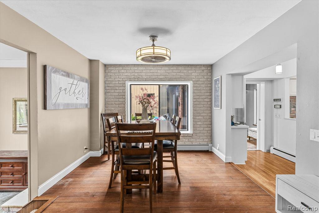 11111 Hibner Road Hartland, MI 48353 - Photo 19 of 59 Dining area featuring a baseboard radiator, hardwood / wood-style flooring, brick wall, and a baseboard heating unit