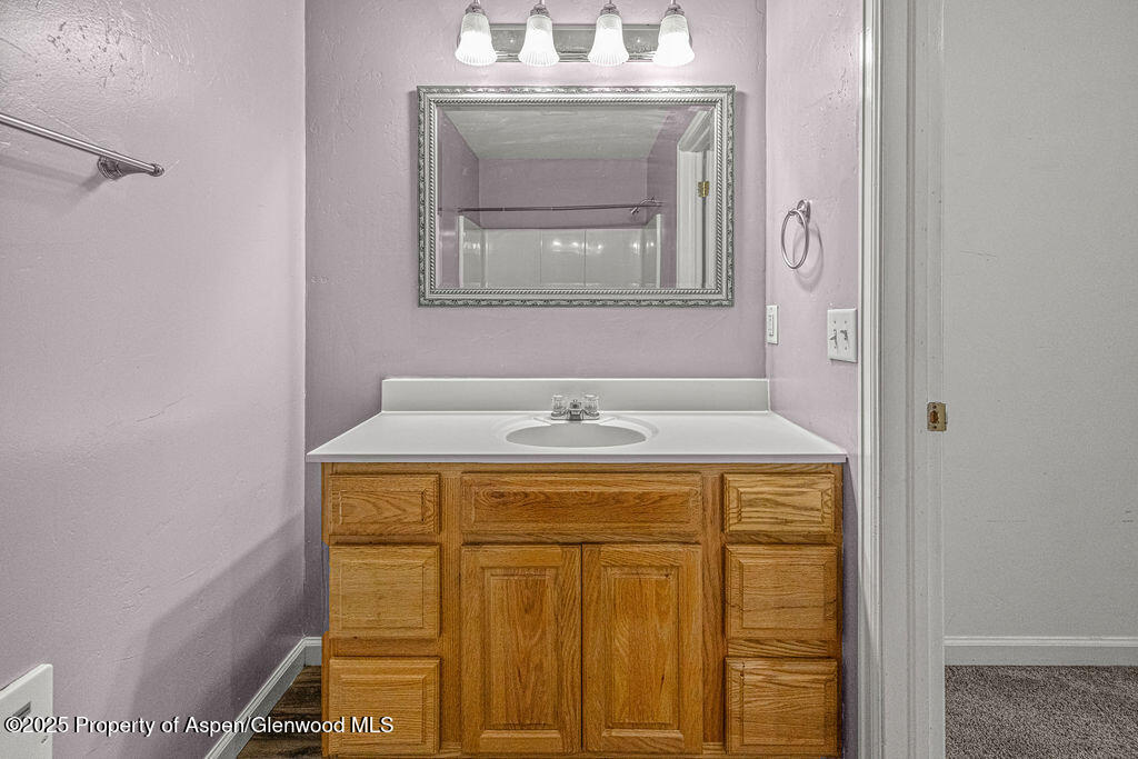 627 Lake Street Rangely, CO 81648 - Photo 22 of 44 a bathroom with a granite countertop sink a mirror and a shower