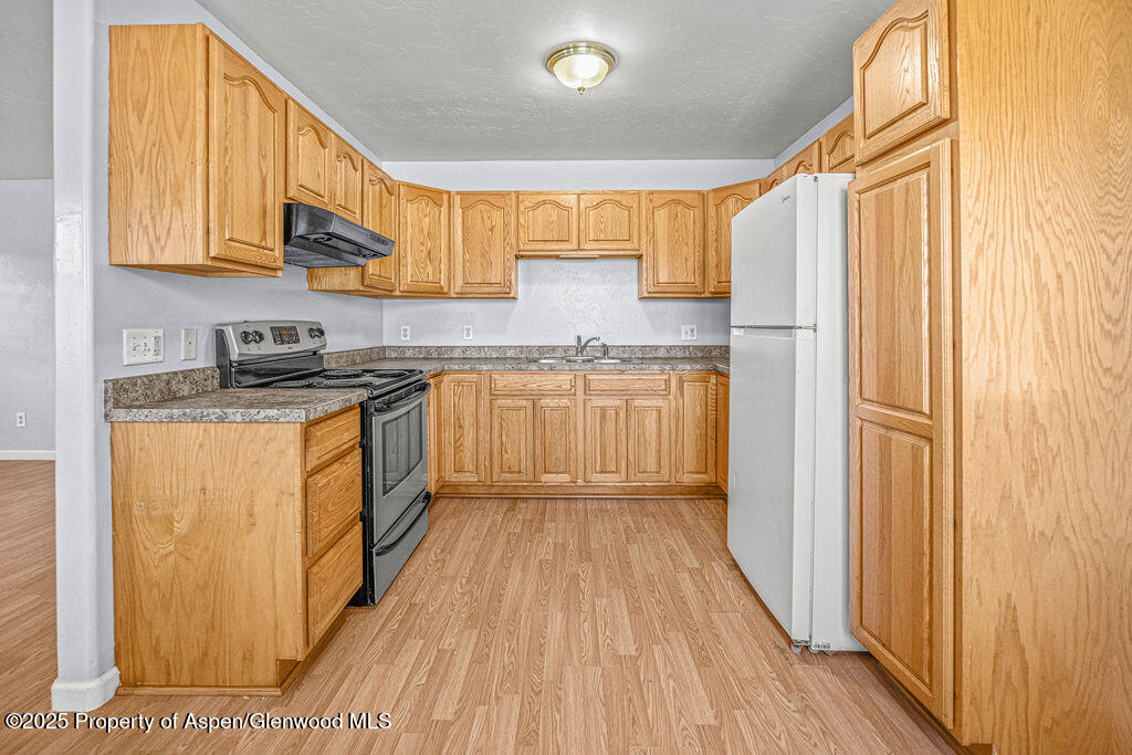 627 Lake Street Rangely, CO 81648 - Photo 6 of 44 a kitchen with stainless steel appliances granite countertop wooden cabinets a window and a sink