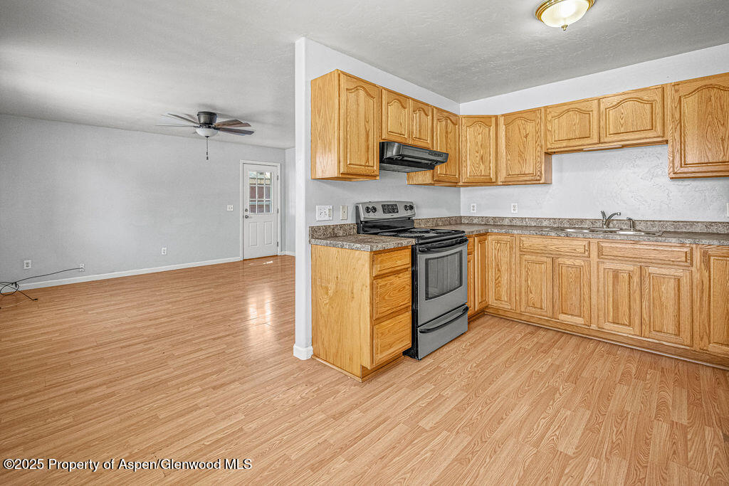 627 Lake Street Rangely, CO 81648 - Photo 8 of 44 a kitchen with stainless steel appliances granite countertop a stove a sink and white cabinets with wooden floor