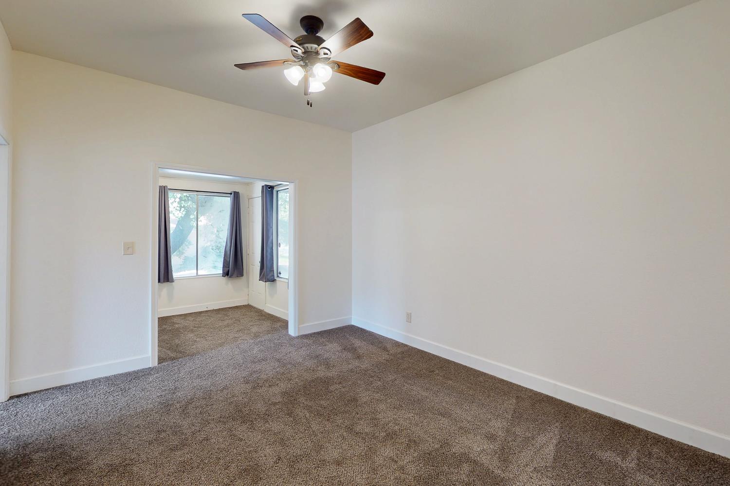 1585 Sycamore Street Gridley, CA 95948 - Photo 25 of 69 an empty room with a chandelier fan and windows