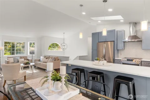 a open kitchen with stainless steel appliances kitchen island granite countertop a sink and a refrigerator