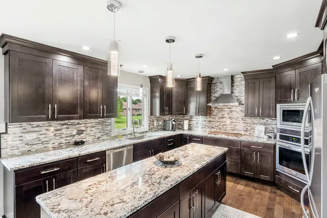 a kitchen with stainless steel appliances kitchen island granite countertop a sink and a stove