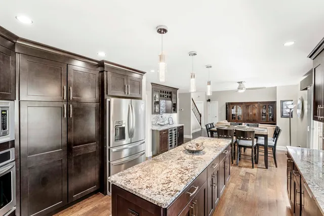 a kitchen with stainless steel appliances granite countertop a refrigerator a stove a sink a dining table and chairs