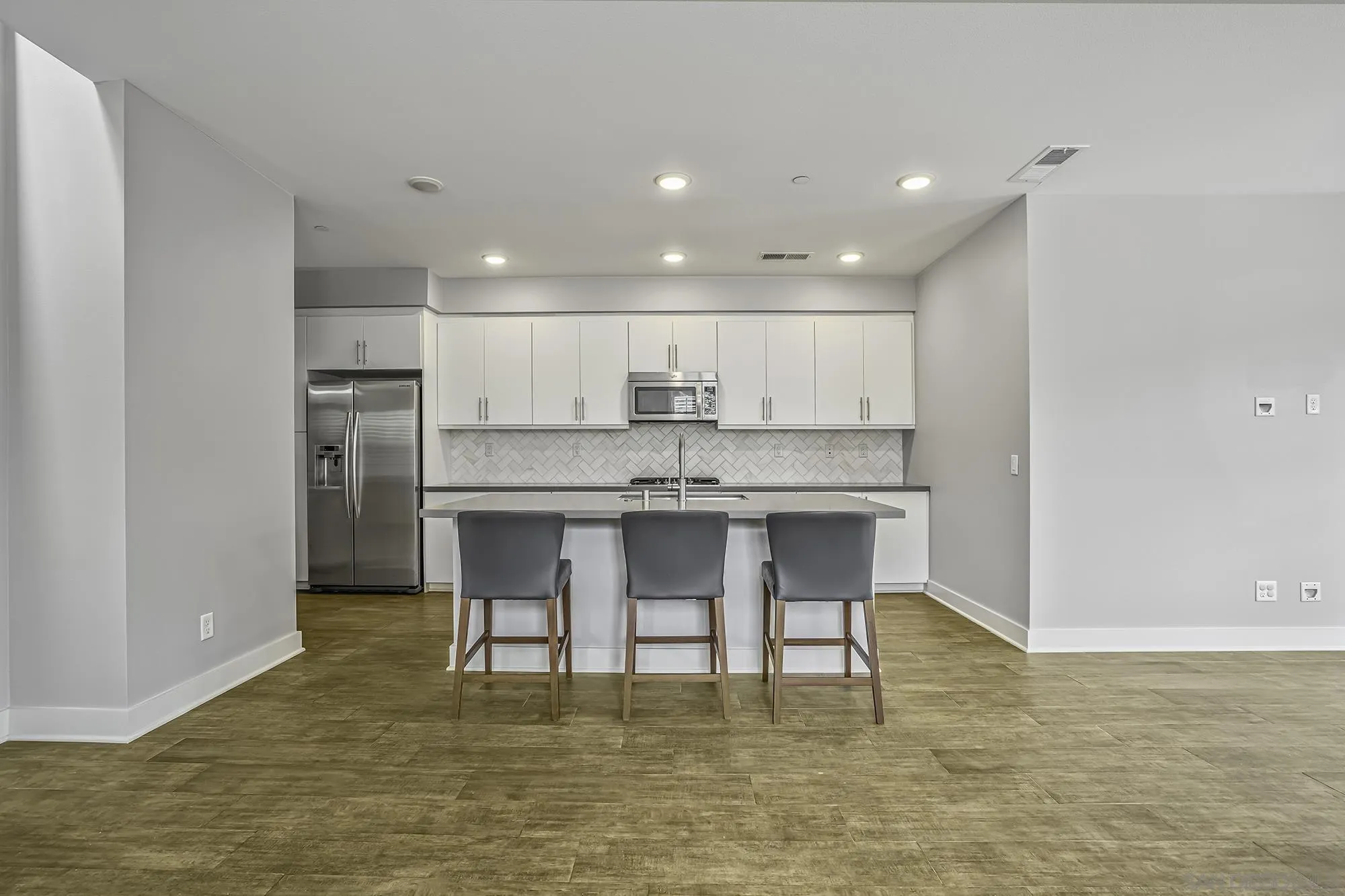 145 Stonesteps Way Encinitas, CA 92024 - Photo 2 of 25 a kitchen with kitchen island granite countertop a stove a sink a refrigerator and white cabinets with wooden floor