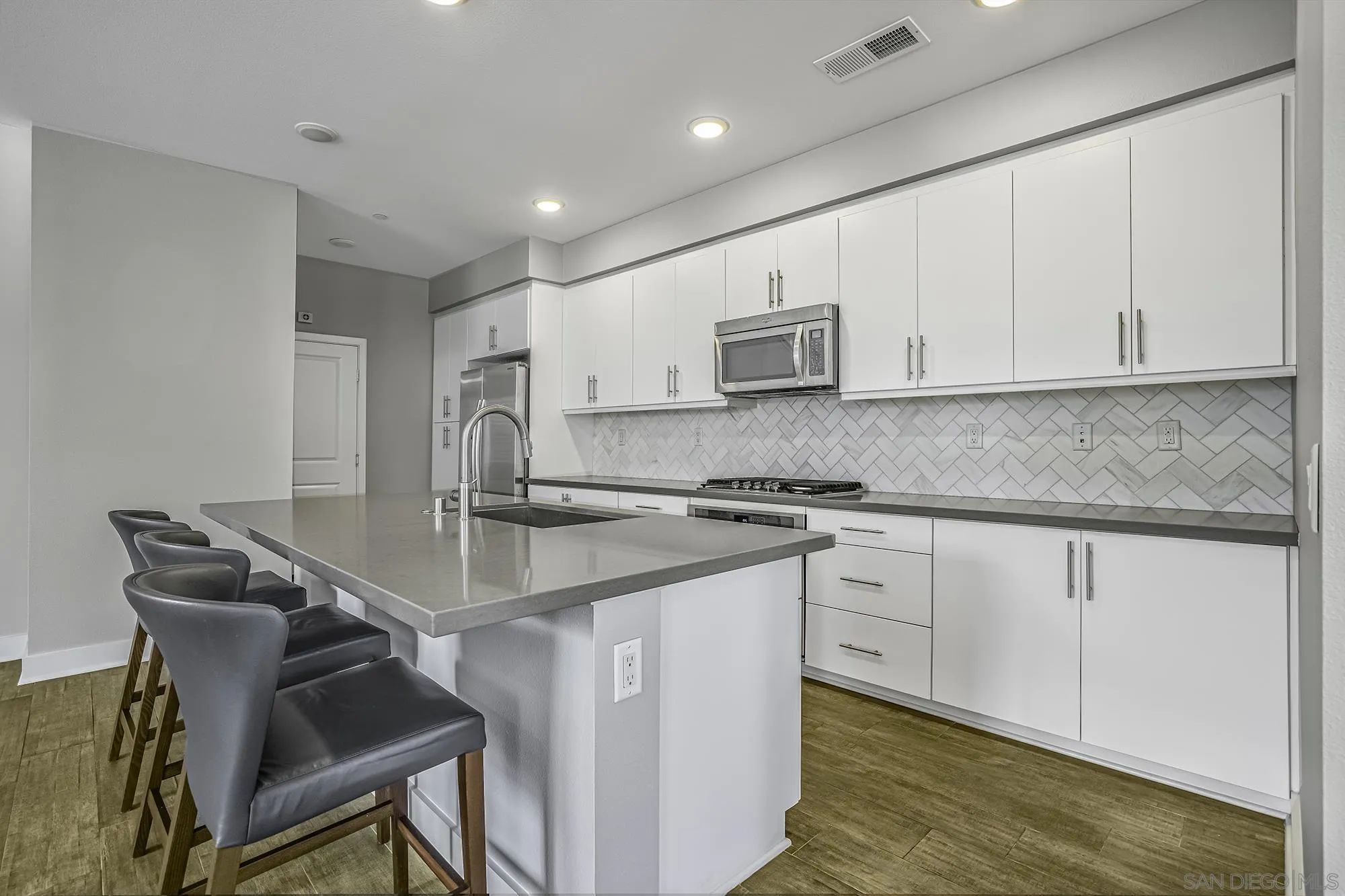 145 Stonesteps Way Encinitas, CA 92024 - Photo 5 of 25 a kitchen with kitchen island a sink stove and white cabinets