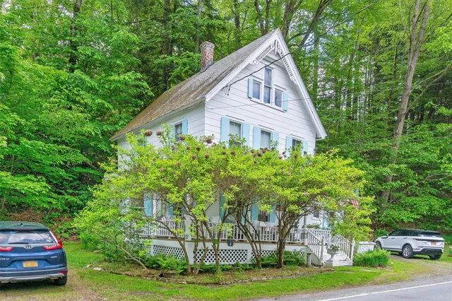 a front view of house with garden and trees