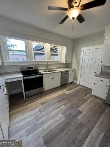 a large kitchen with granite countertop a stove and cabinets