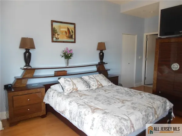 a bedroom with a bed and a flat tv screen on a dresser