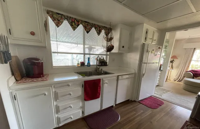 a kitchen with stainless steel appliances a sink a refrigerator and wooden floor