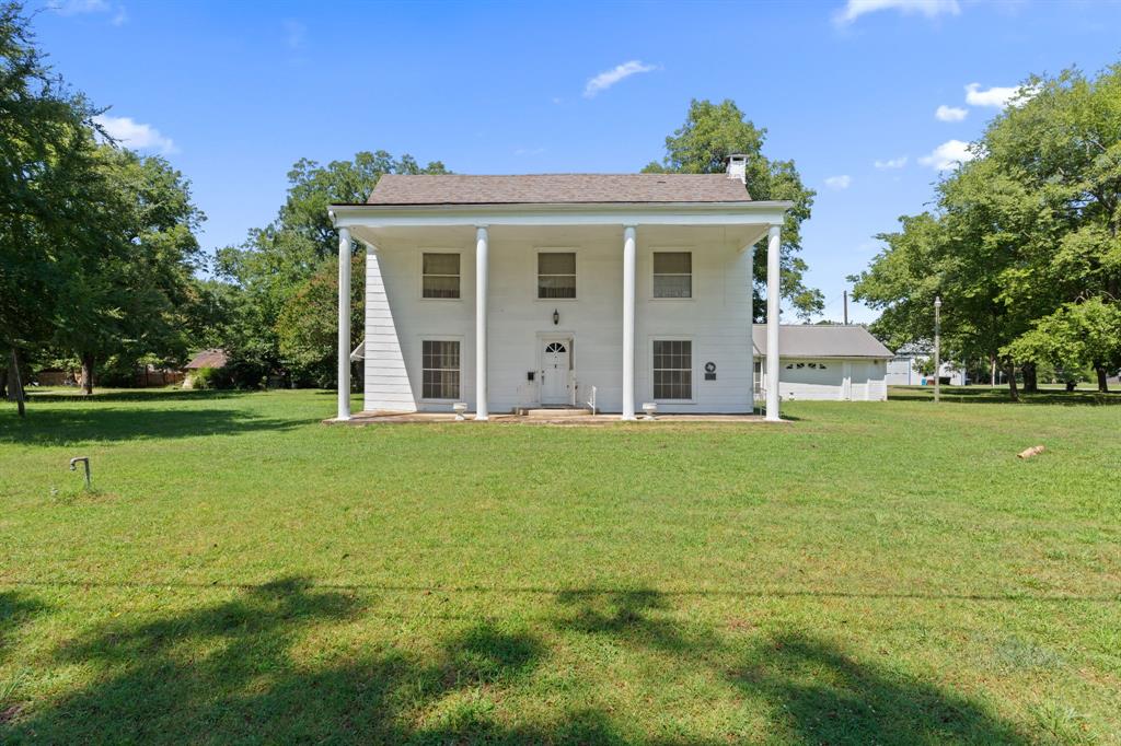 a view of a white house with a large garden