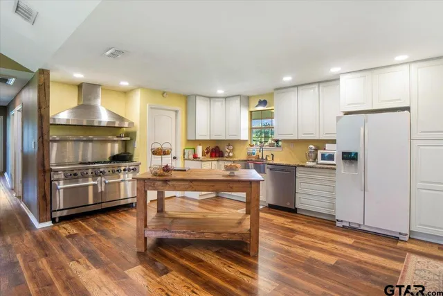 a kitchen with kitchen island granite countertop a stove a sink and a refrigerator