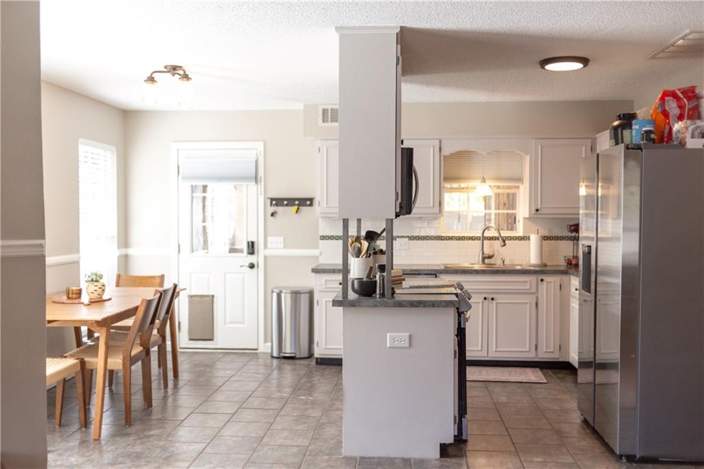 280 Mimosa Road Phenix City, AL 36870 - Photo 5 of 38 Kitchen featuring stainless steel refrigerator with ice dispenser, white cabinetry, light tile patterned floors, backsplash, and a textured ceiling