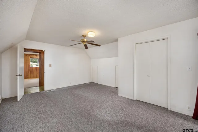 a view of an empty room and a chandelier fan