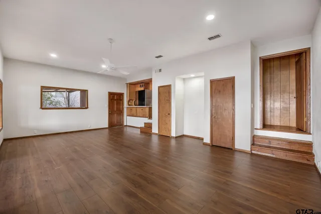 a view of a big room with wooden floor and windows