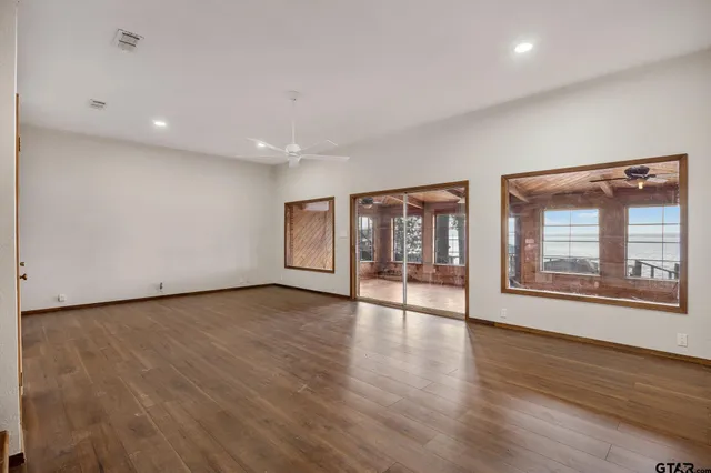 a view of an empty room with wooden floor and windows