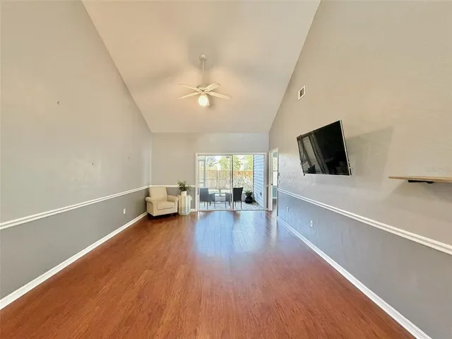 a view of empty room with wooden floor and fan