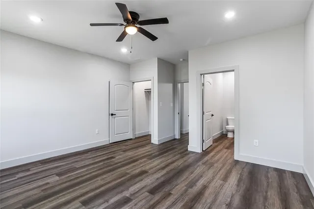 an empty room with wooden floor and a ceiling fan