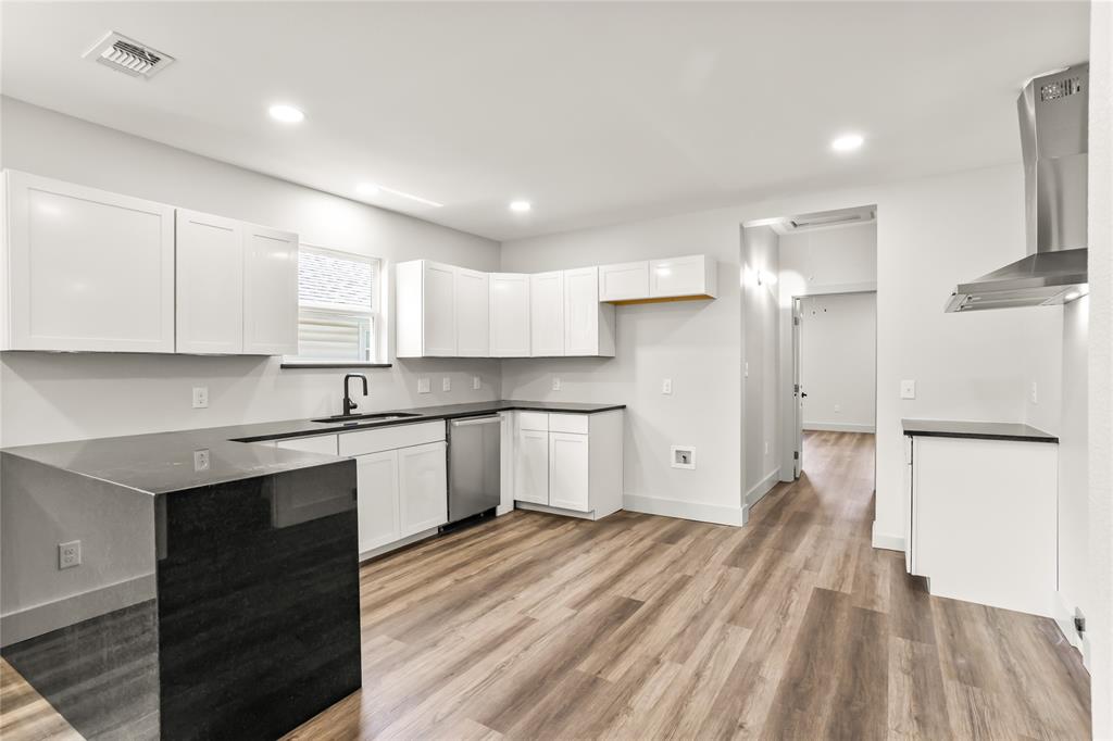 1127 West Morgan Street Denison, TX 75020 - Photo 3 of 23 a large kitchen with a refrigerator a sink dishwasher a stove and white cabinets with wooden floor