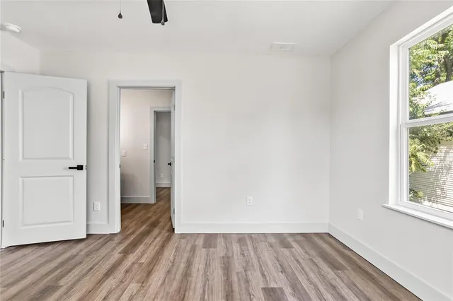 a view of an empty room with wooden floor and a window