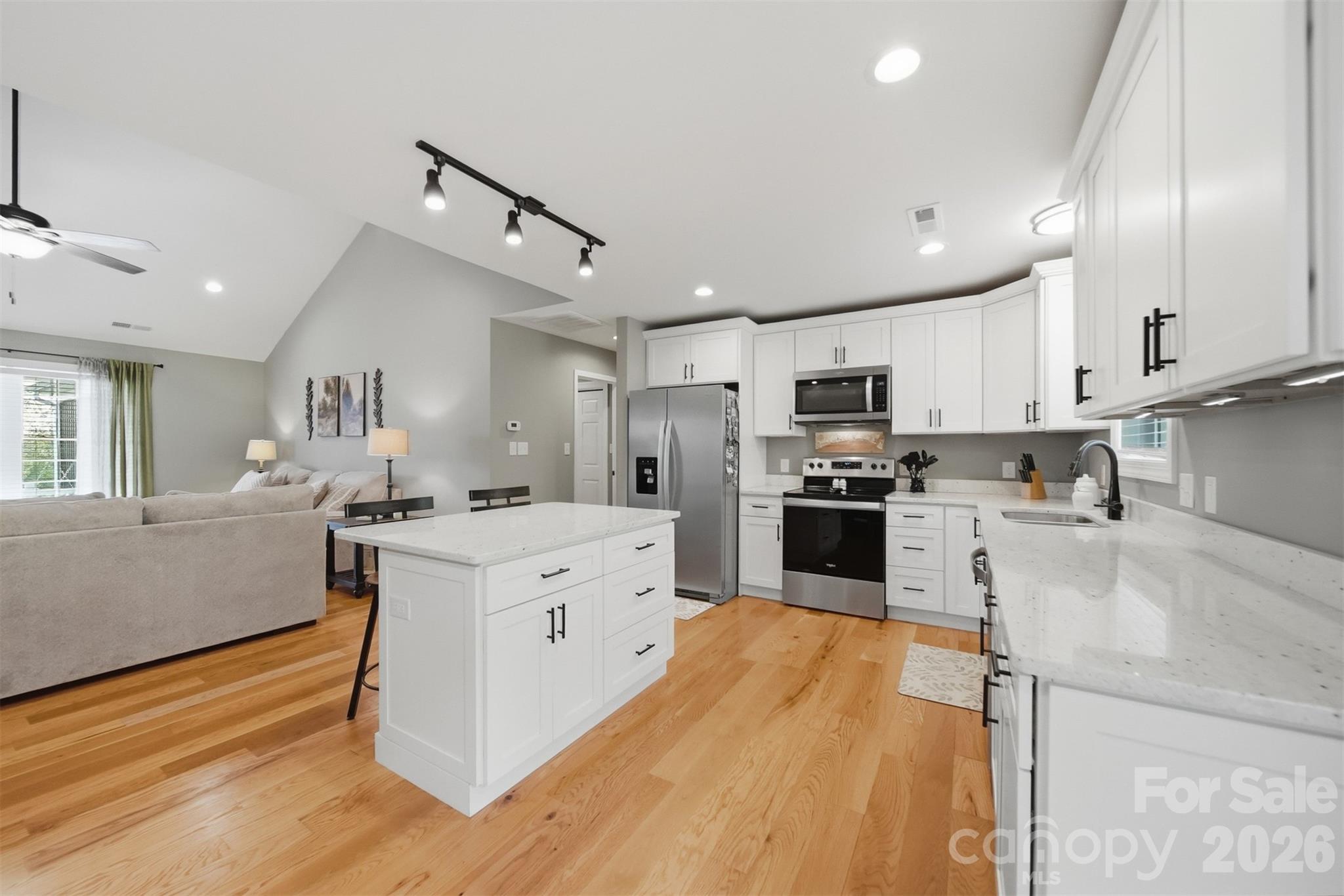 490 Dudley Shoals Road Granite Falls, NC 28630 - Photo 11 of 38 a large kitchen with stainless steel appliances kitchen island granite countertop a stove a sink a refrigerator and white cabinets with wooden floor