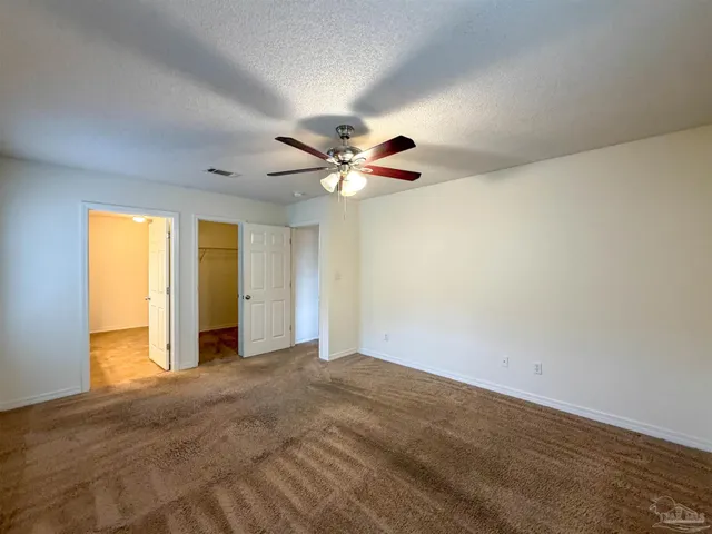 an empty room with a ceiling fan and window