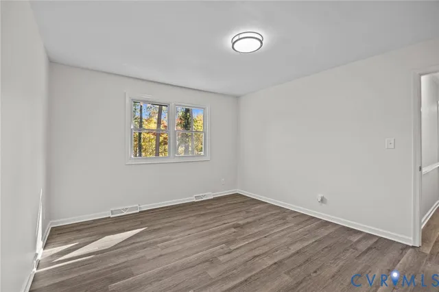 an empty room with wooden floor and window