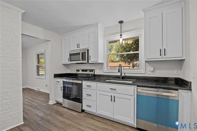 a kitchen with stainless steel appliances granite countertop a stove a sink and white cabinets