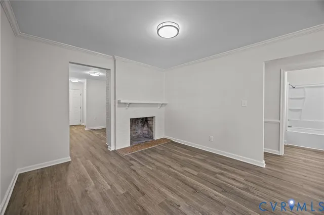 a view of empty room with wooden floor and fireplace