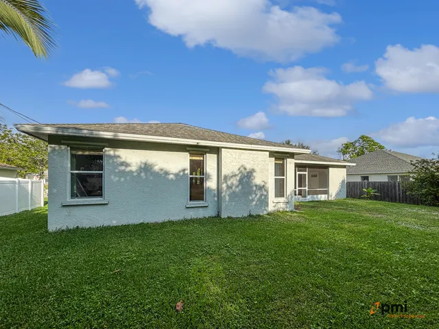 a backyard of a house with plants and large tree