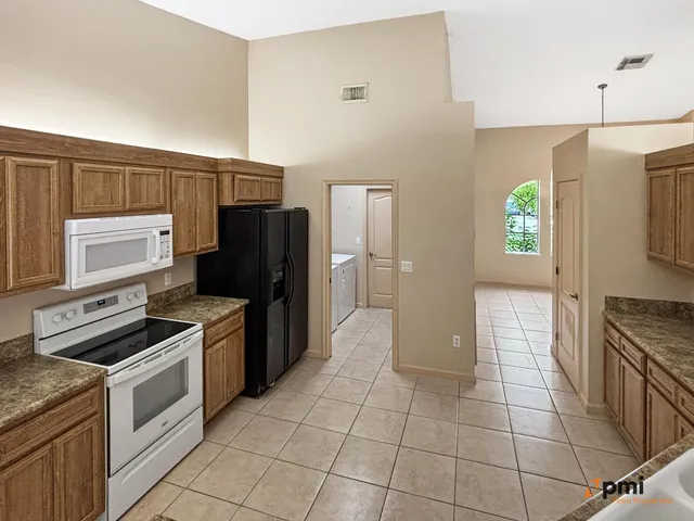 a kitchen with granite countertop a refrigerator and a stove top oven