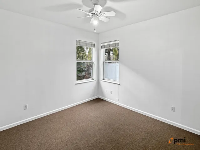 a view of a livingroom with a chandelier fan and windows
