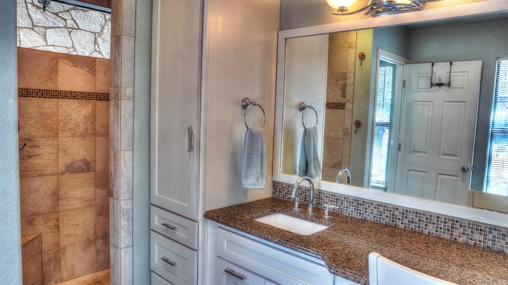 187 Roy Chisum Road Leakey, TX 78873 - Photo 17 of 40 a bathroom with a granite countertop shower and a sink