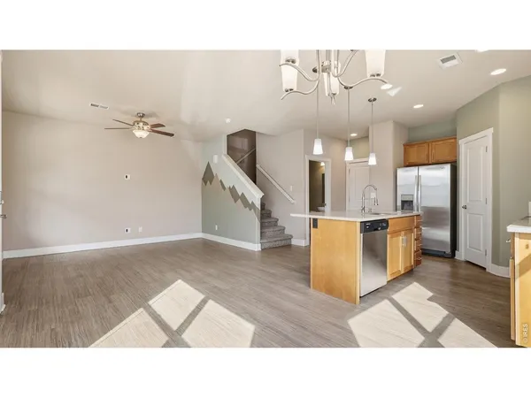 a living room with couches and kitchen view with wooden floor