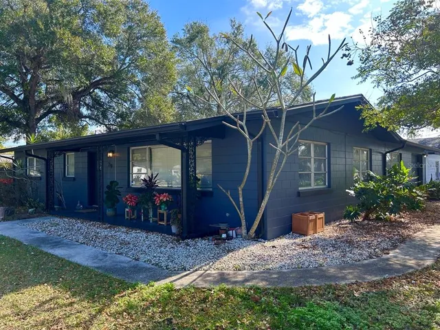 a view of a house with a yard and large tree