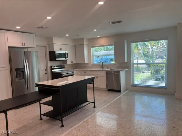 a kitchen with stainless steel appliances a stove a sink a refrigerator and a microwave