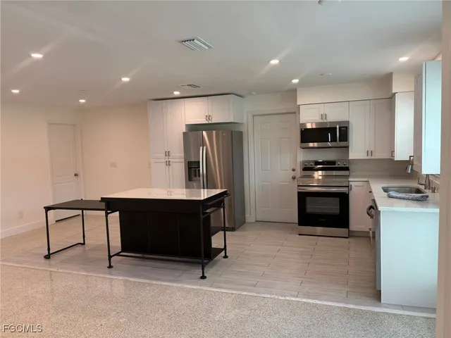 a kitchen with kitchen island white cabinets and stainless steel appliances
