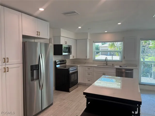 a kitchen with stainless steel appliances kitchen island granite countertop a refrigerator stove top oven and sink