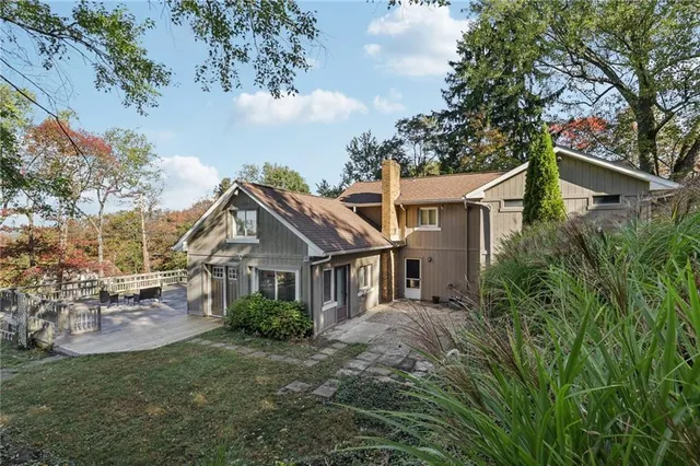 a view of a white house next to a yard with big trees