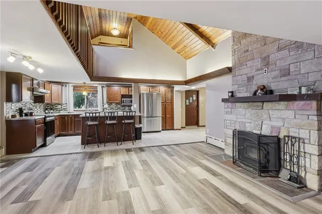 a living room with stainless steel appliances kitchen island granite countertop furniture and fireplace