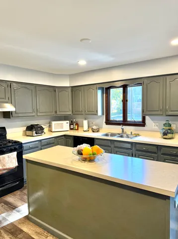 a kitchen with stainless steel appliances granite countertop a sink dishwasher stove and white countertops with wooden floor
