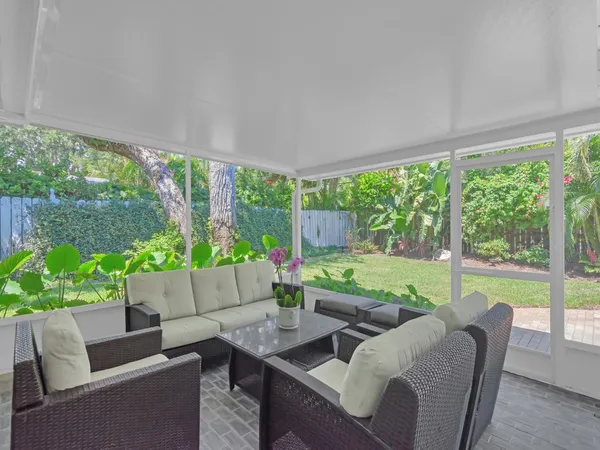 a living room with patio furniture and garden view