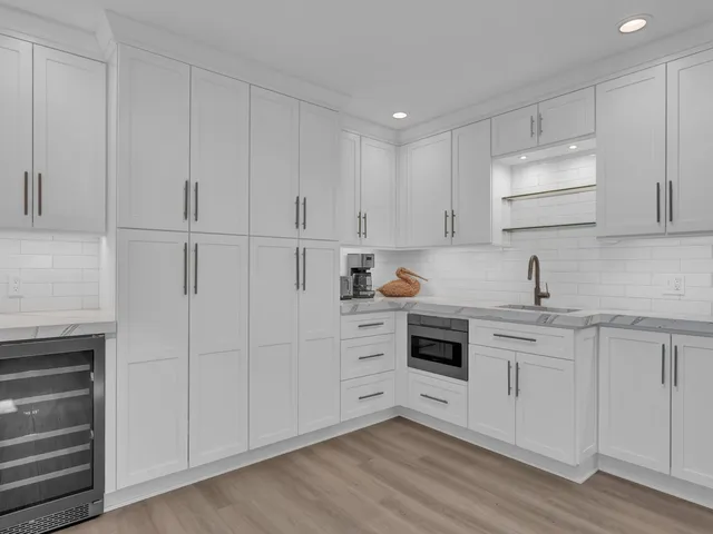 a kitchen with white cabinets and sink