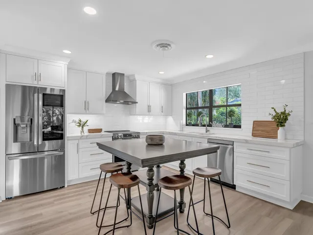 a kitchen with stainless steel appliances a dining table chairs refrigerator and stove