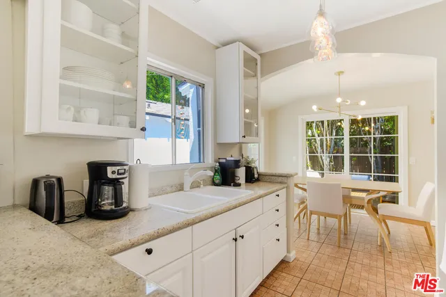 a very nice looking kitchen with granite countertop a stove a sink a dining table and chairs