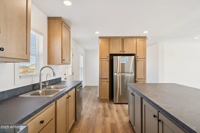 a kitchen with a sink dishwasher a refrigerator and cabinets with wooden floor