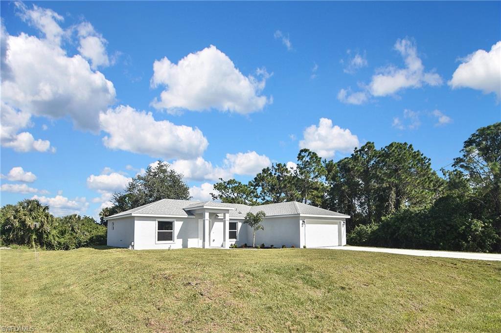 3306 1st Street Southwest Lehigh Acres, FL 33976 - Photo 1 of 47 a front view of a house with a yard and garage