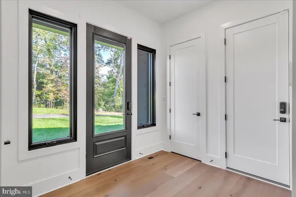 a view of an empty room with wooden floor and windows