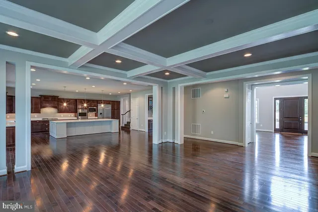 a view of a hallway with wooden floor and a refrigerator