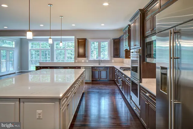 a large kitchen with kitchen island a large counter top space a sink a refrigerator and windows